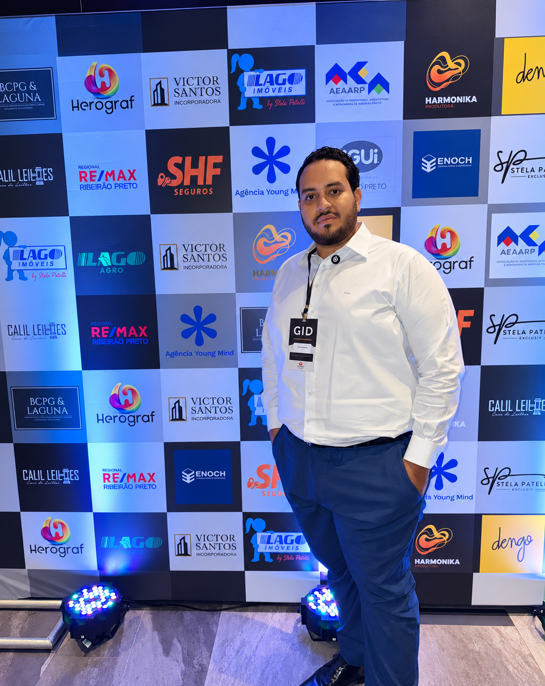 Victor em um evento de negócios, diante de um painel de marcas